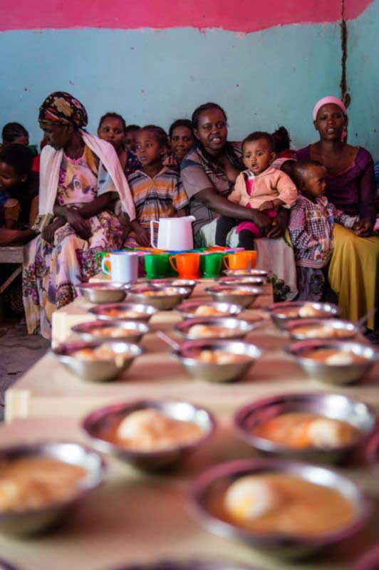 A group of women and their children being served a meal