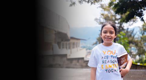 A girl holding her bible and smiling