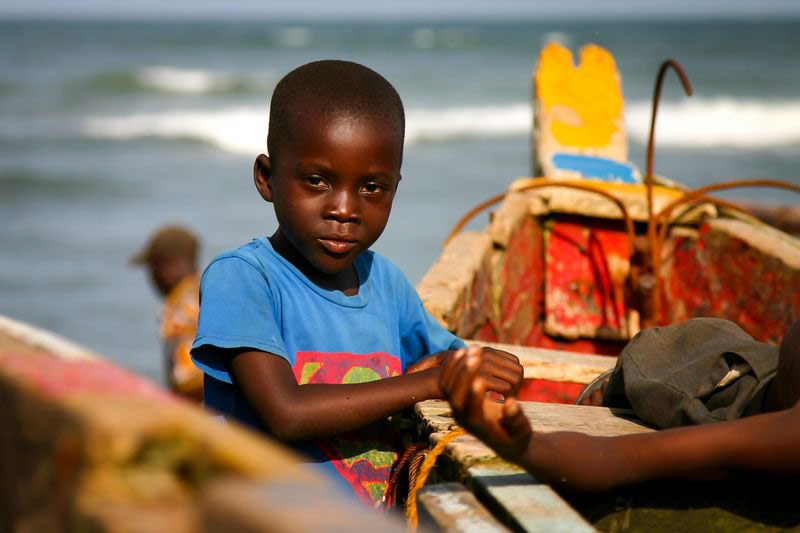 A boy stands near a boat