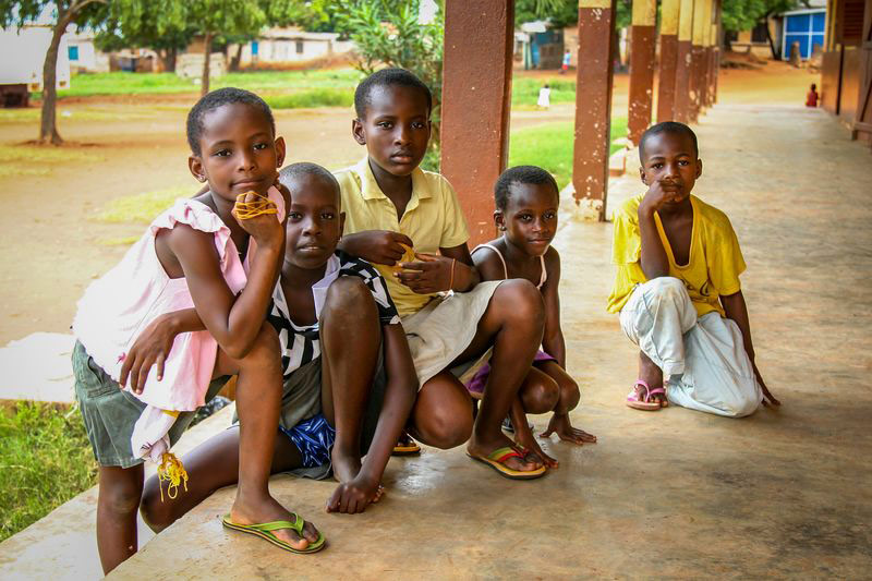 Kids kneel outside a center and smile