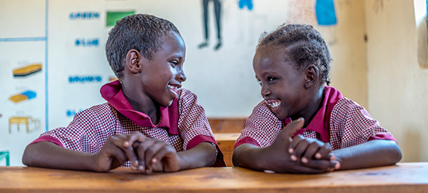 Two students smile to eachother in a classroom