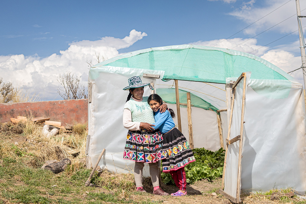 a girl hugs her mother in front of a greenhouse