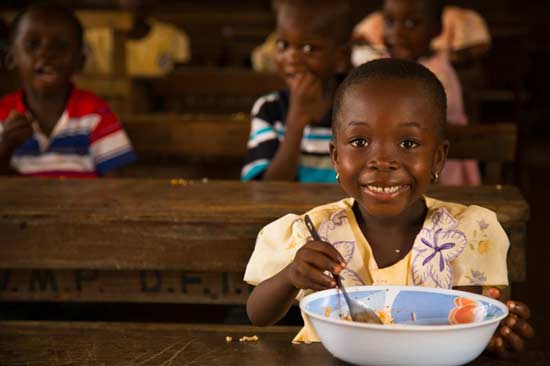 Girl smiling while eating at a table