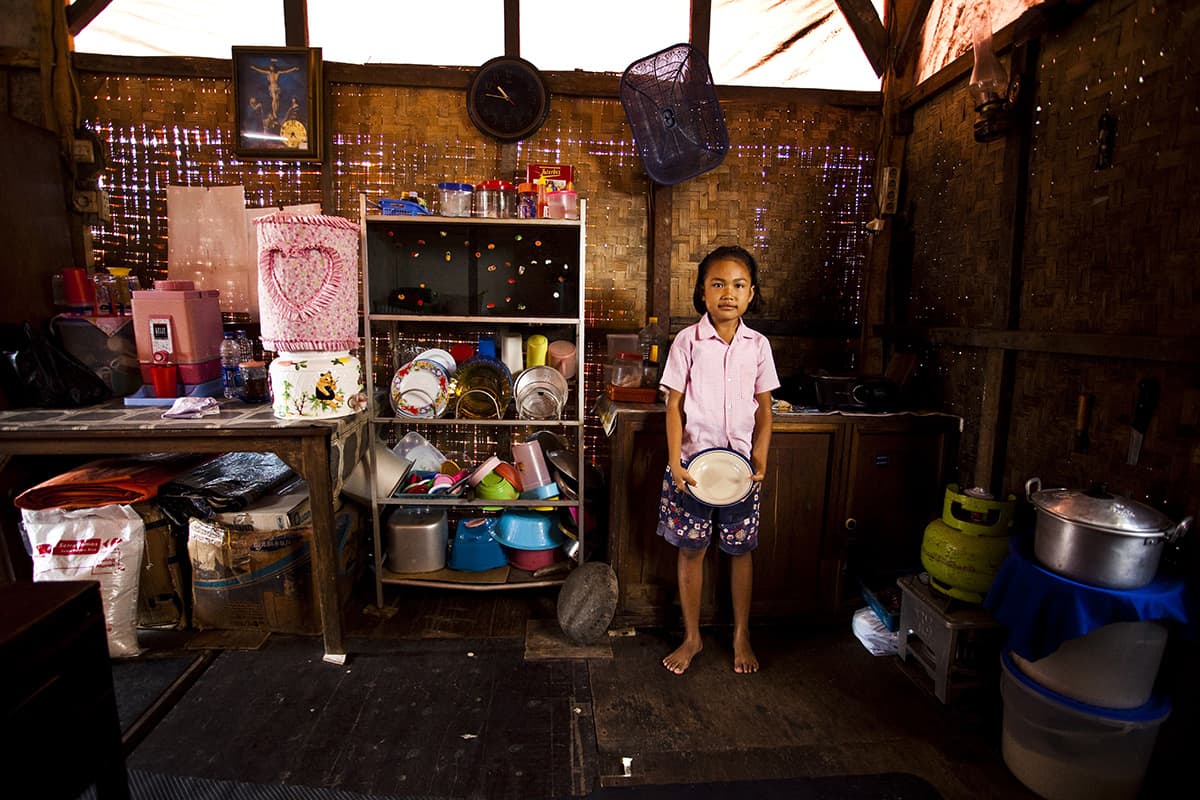 A girls stands in a kitchen holding a serving bowl