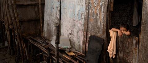 A boy peeks over a plywood door