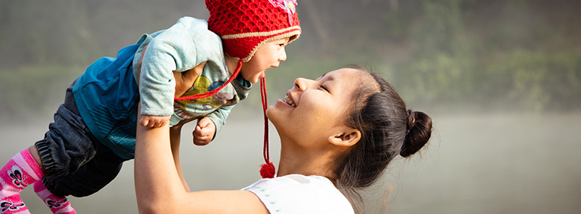 a mother holds up and smiles at her baby