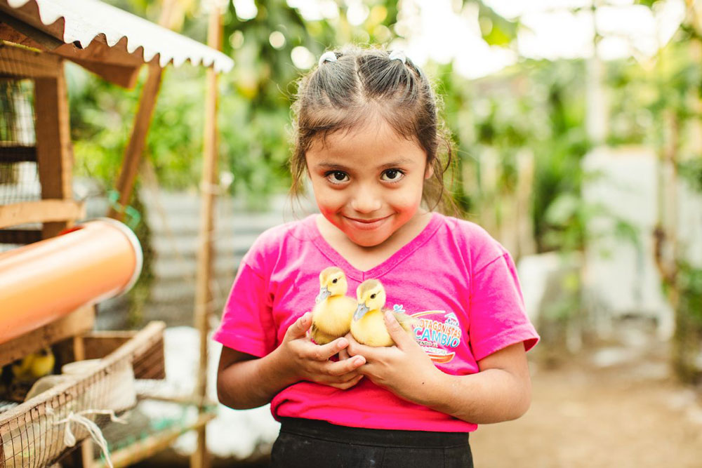 A young girl holds two ducklings in her hands