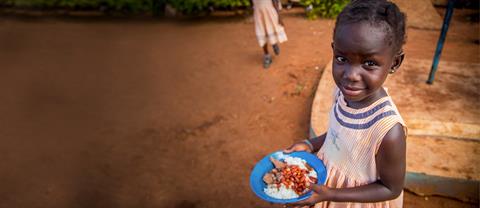 A girl sits with a plate of food