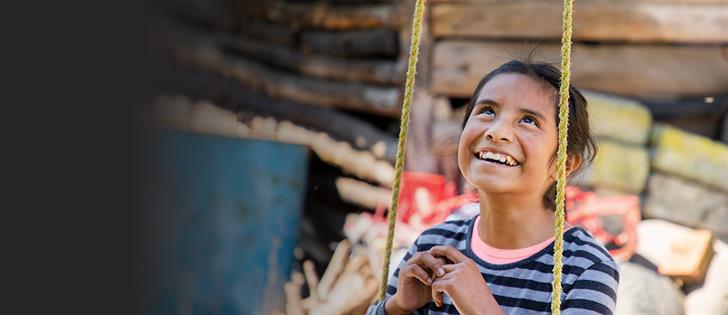 A girl sits on a swings smiling