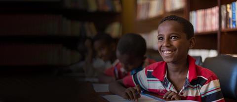 A boy smiling while writing a letter