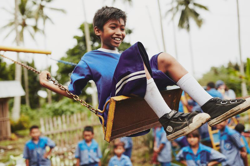 A boy smiles and swings on the playground