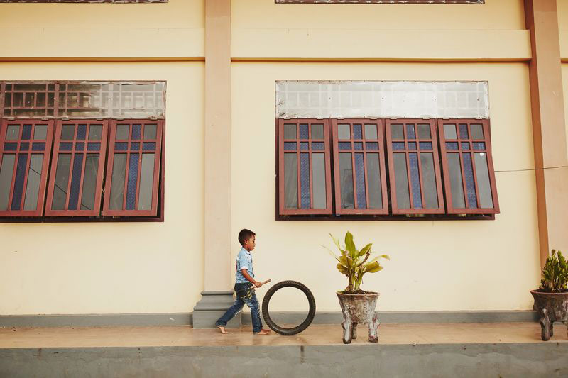 A boy pushes a wheel with a stick