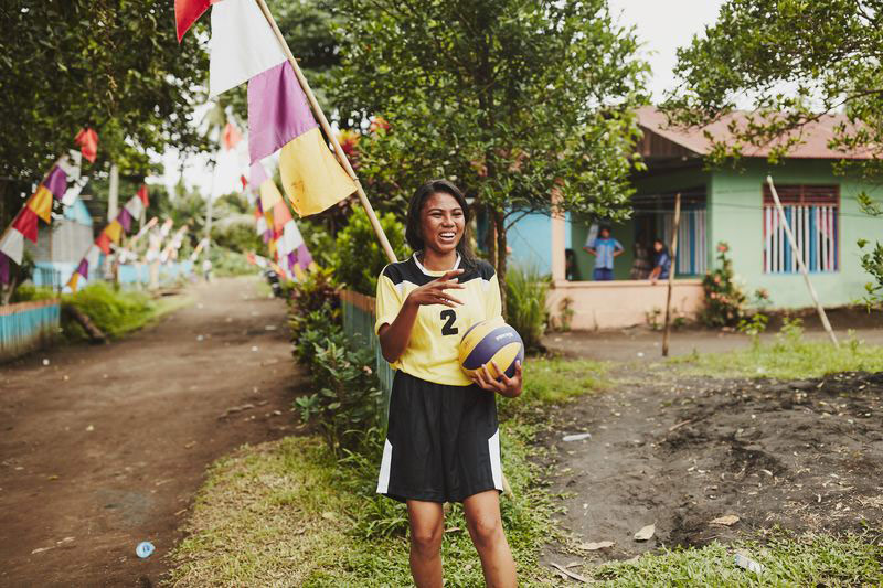 A young lady stands holding a soccer ball