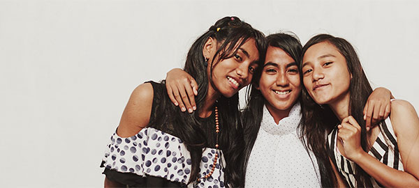 Three Indonesian teenage girls stand together with their heads placed together