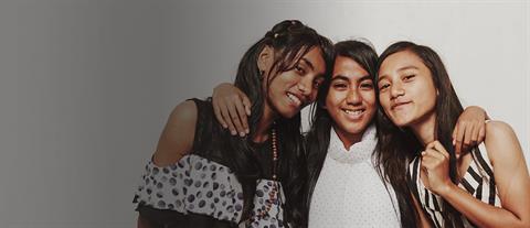 Three Indonesian teenage girls stand together with their heads placed together