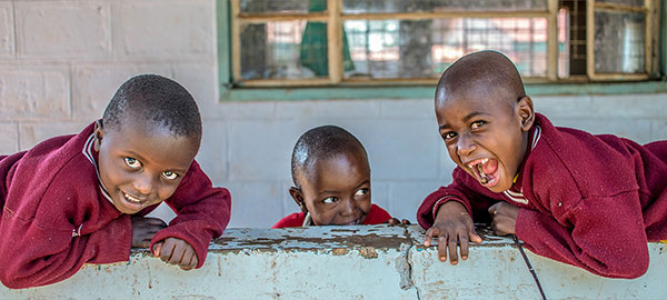 Two smiling boys in red sweaters lie on a wall