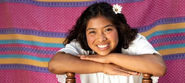 Girl sits smiling at the camera.