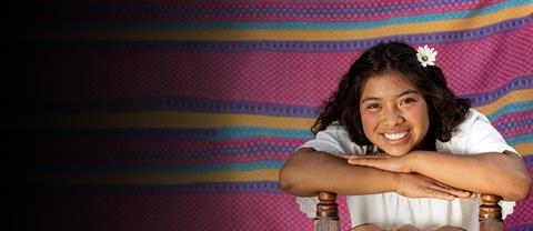 A young woman sits on a chair smiling