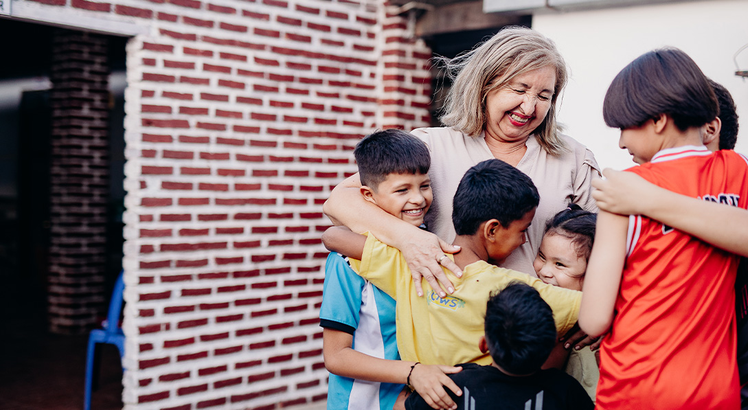  A smiling woman stands with a group of six young boys as they all join together for a group hug