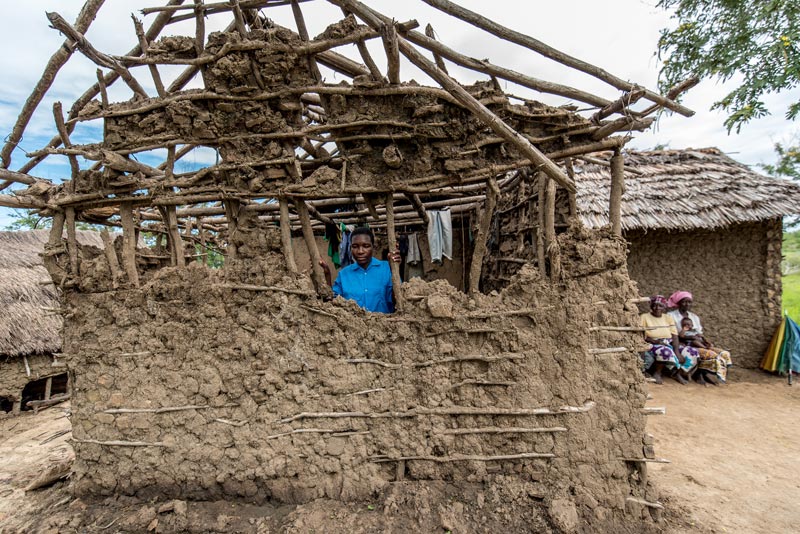 A woman stands inside the remains of her home after a flood