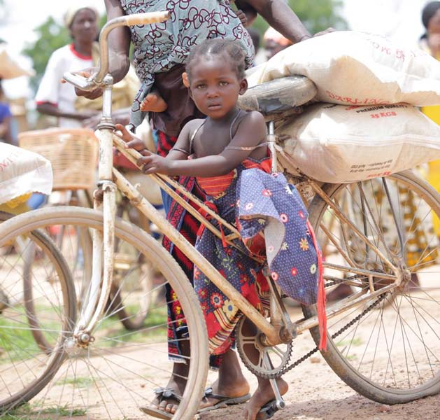 A young girl walks with her mother after receiving food