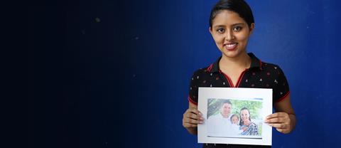 A girl smiling and holdind a drawing