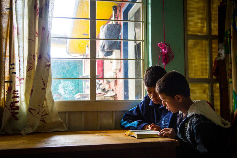 Two friends sit at a table and read their Bible together