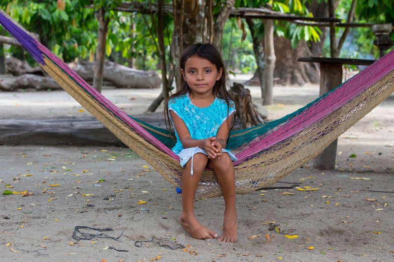 A girl sits in a hammock and smiles