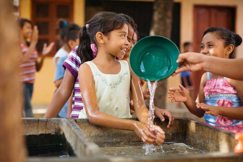 A young girl washes her hands with water from the new water tank installed at her child development center