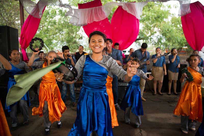 A group of girls play tambourines and dance together