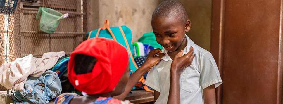 Woman straightening the collar of a smiling boy.