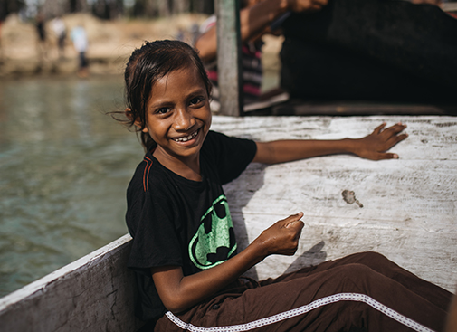 A young girl sits on a chair smiling