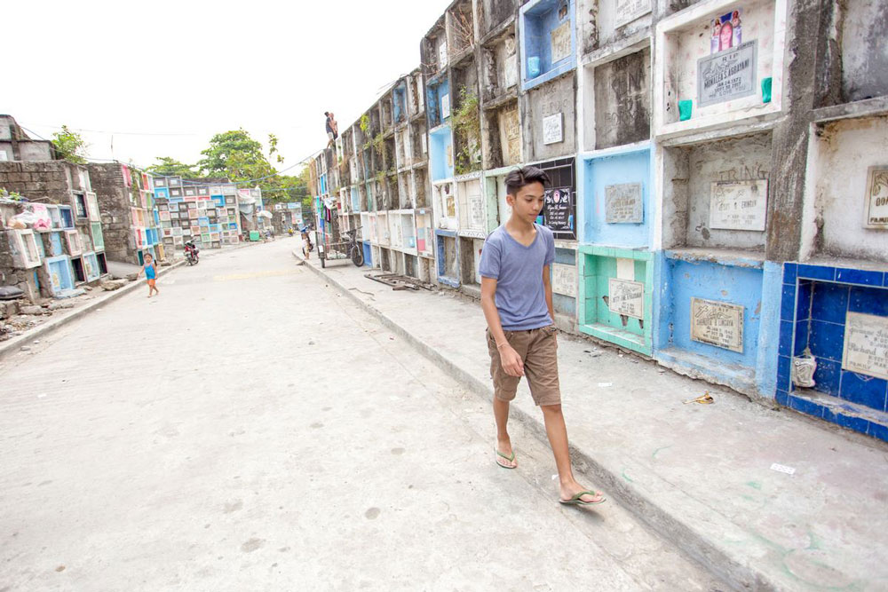 A boy walks near a cemetery