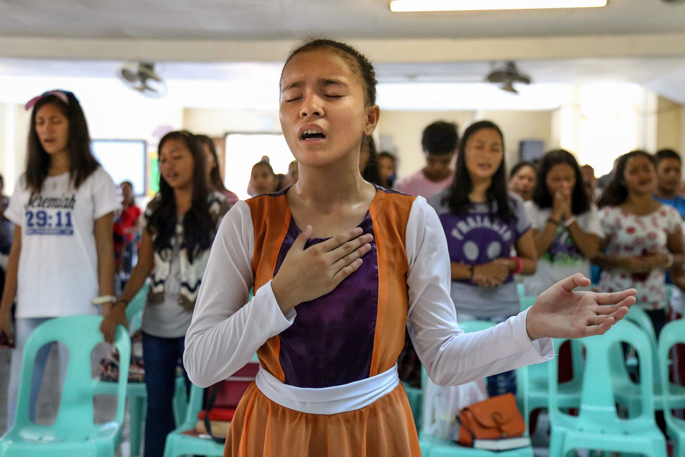 A group of children sing and worship together