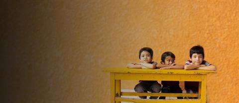 Three kids sitting at a desk