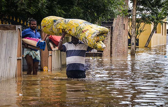 a man carries a mattress on his head while walking in waist deep water