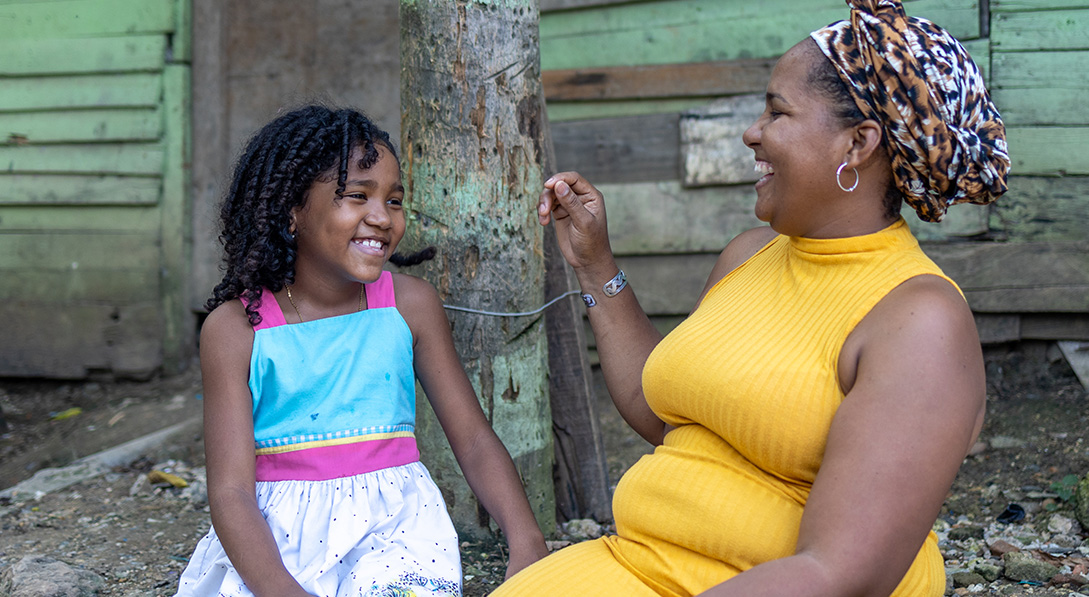 Mother and daughter sitting outside smiling at each other