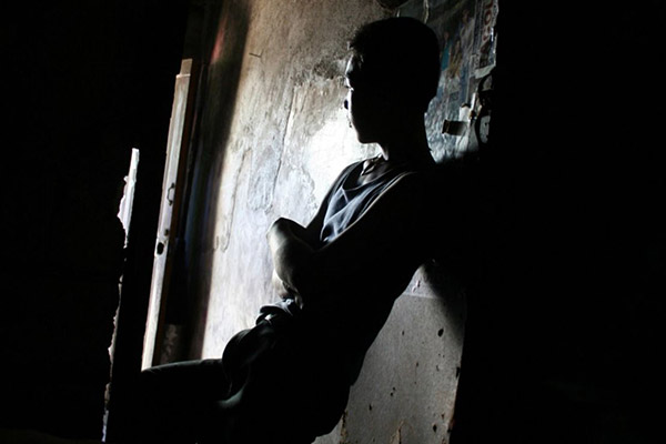 A young man leaning against the wall looking outside