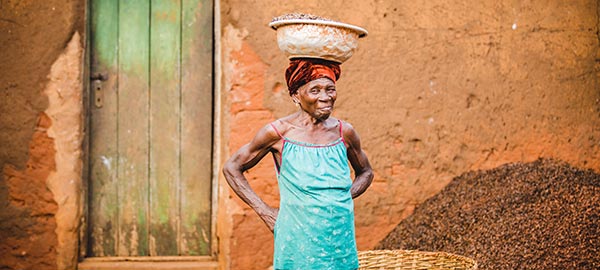 A elderly woman balances a basket on her head