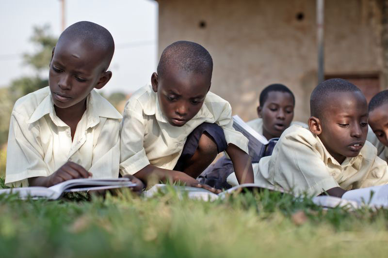 A group of boys stretch out in the grass reading