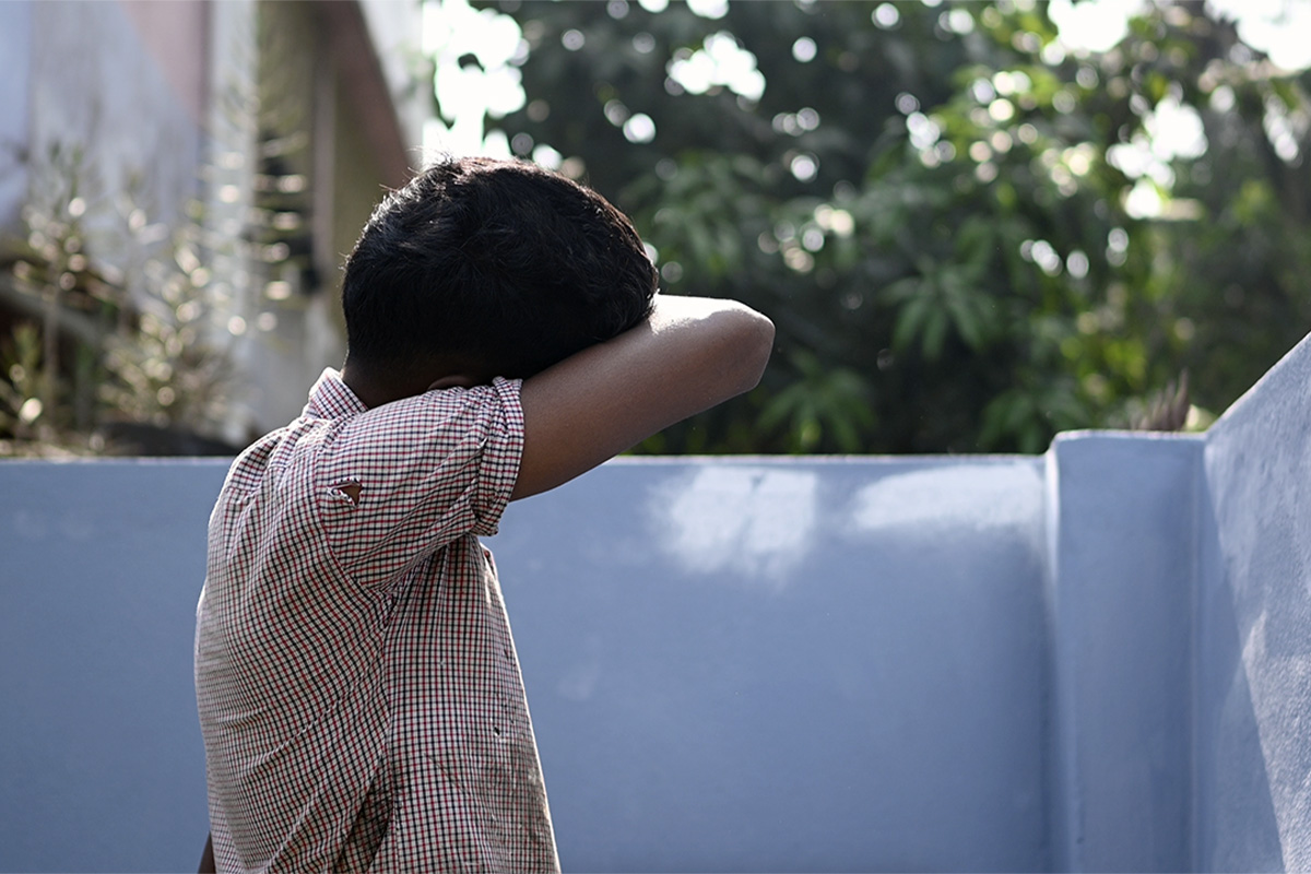 A young boy stuck in child labor wipes the sweat from his face using his sleeve.