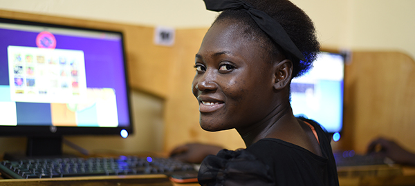 a young woman sits in front of a computer screen