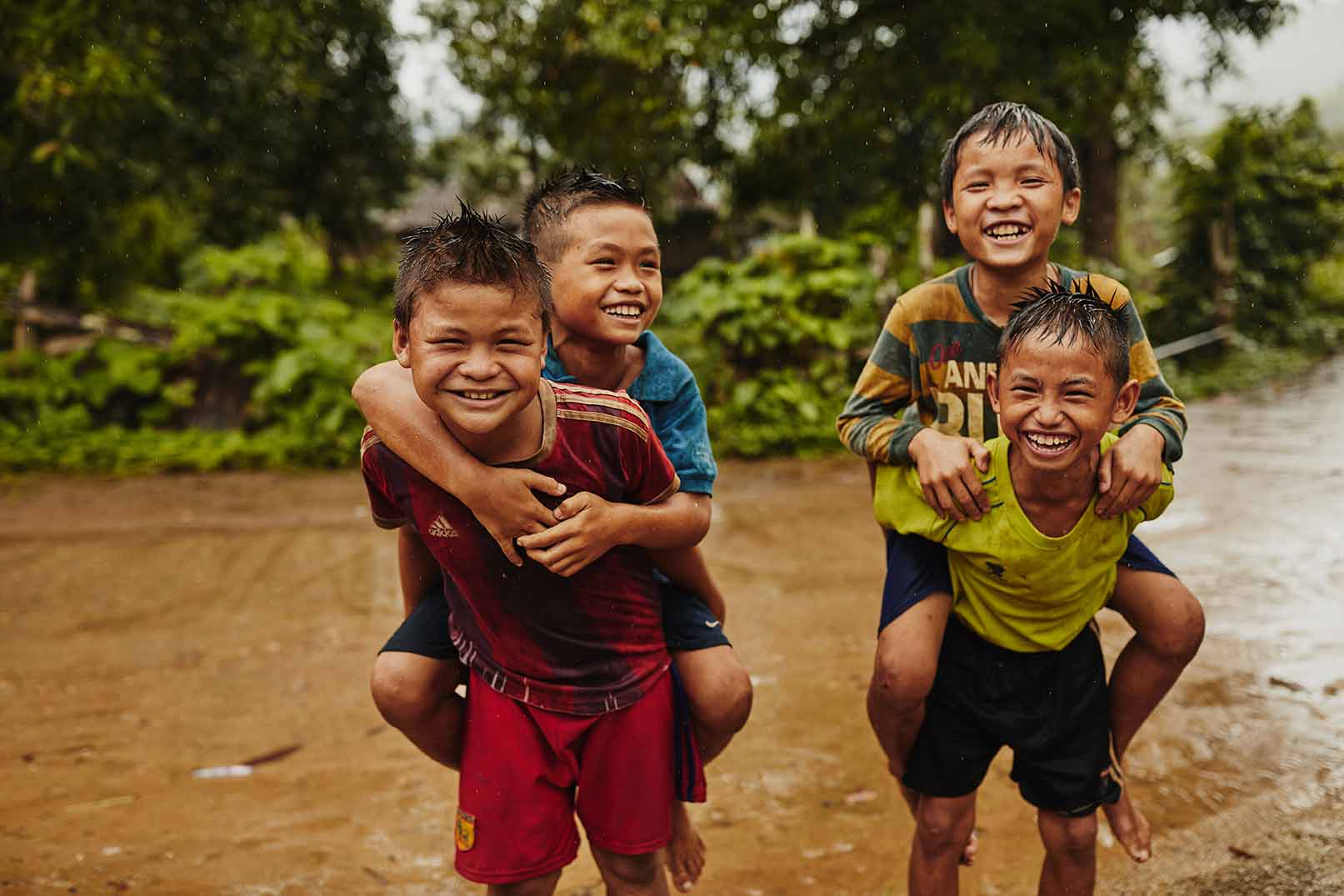 Two smiling and laughing boys give piggyback rides to two other boys