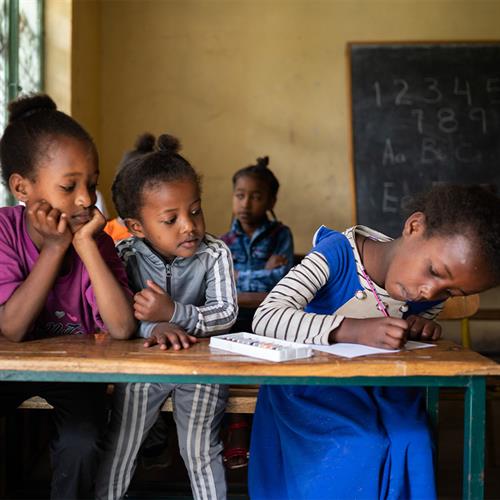 child writes a letter while other children watch 