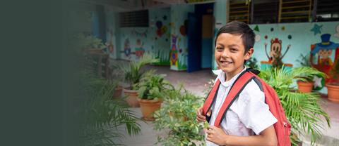 A boy smiles with a backpack on