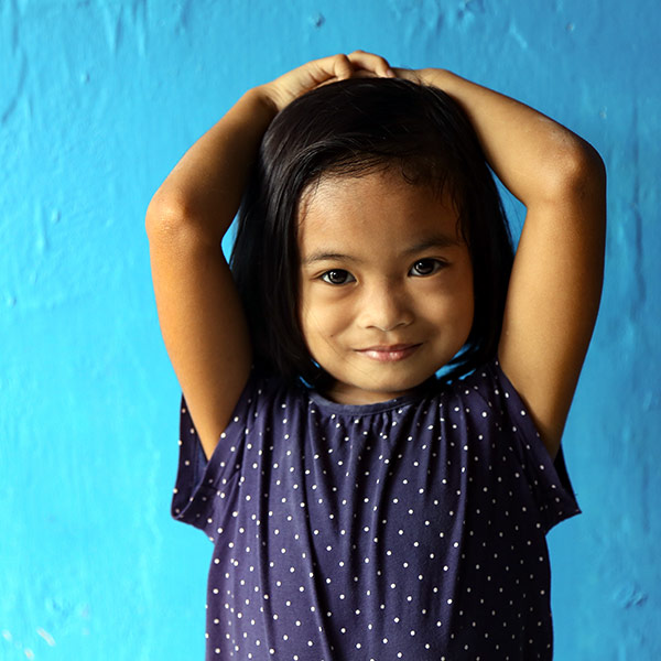 A young girl stands with her hands on her head