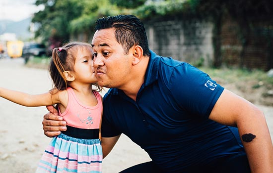 A little girl gives a man a kiss on the cheek