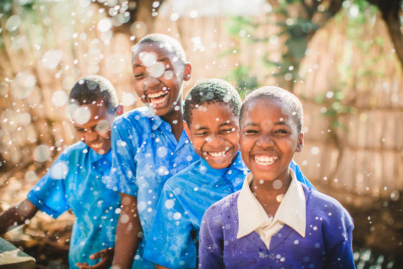 Children laugh while playing in water