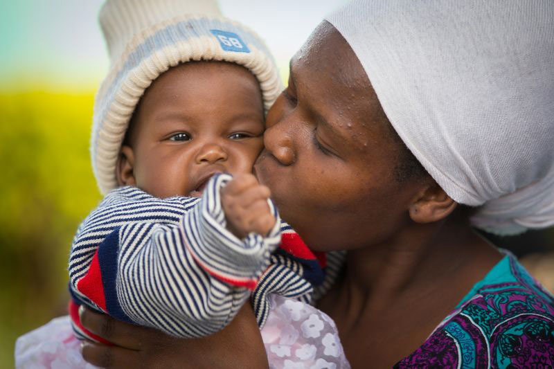 A mother lovingly kisses her newborn baby