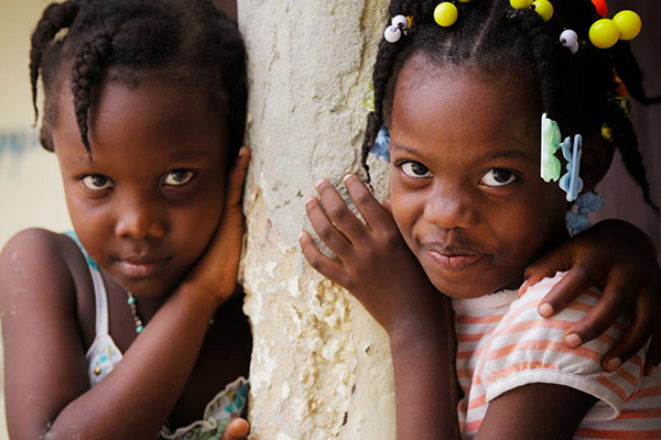 Two girls standing around a cement post